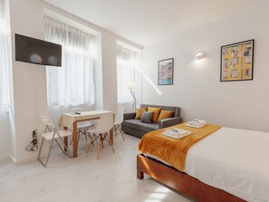 A hotel room with a bed, a desk, a sofa, and a TV. - Apartment  by Interhome (Porto)