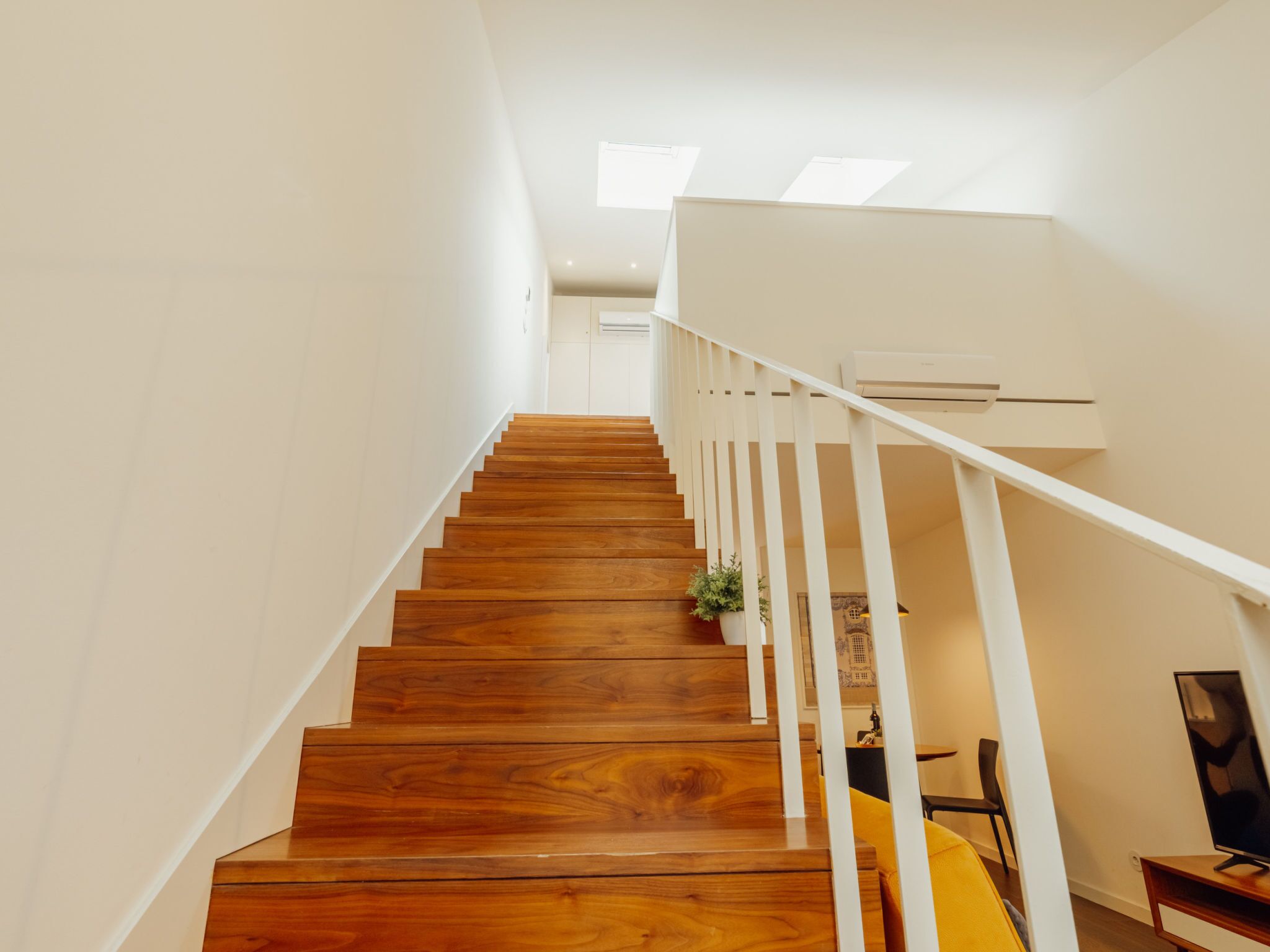 A wooden staircase with white railings leading to a landing.