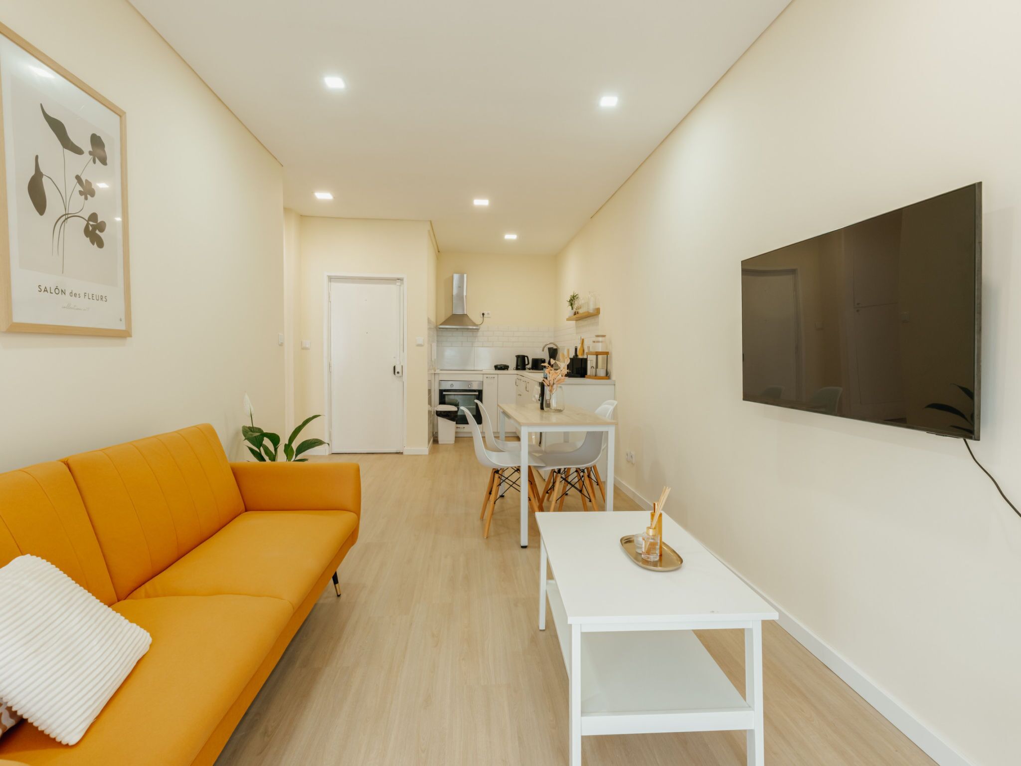 Una sala de estar moderna con un sofá, una mesa de comedor y una cocina al fondo.