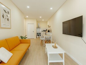 Ein modernes Wohnzimmer mit einer Couch, einem Esstisch und einer Küche im Hintergrund.