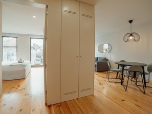 A modern interior with a wooden floor, a dining area with a table and chairs, a sofa, and a wardrobe with a sliding door. - Apartment  by Interhome (Porto)