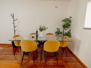 A dining area with a glass table, yellow chairs, a white vase with plants, and a coat rack. - Apartment  by Interhome (Porto)