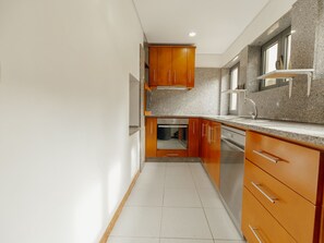 A kitchen with wooden cabinets, a stainless steel sink, and a granite countertop. - Apartment  by Interhome (Porto)