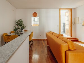 A modern living room with a sofa, a dining table with chairs, a kitchen area, and a large window. - Apartment  by Interhome (Porto)