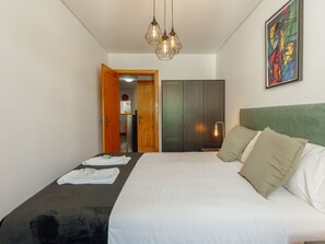 A hotel room with a bed, a painting, a wardrobe, and a door leading to a bathroom. - Apartment  by Interhome (Porto)