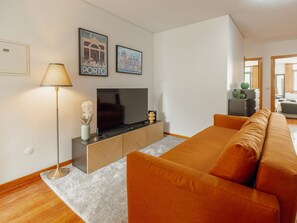 A modern living room with a sofa, a TV, and decorative items. - Apartment  by Interhome (Porto)