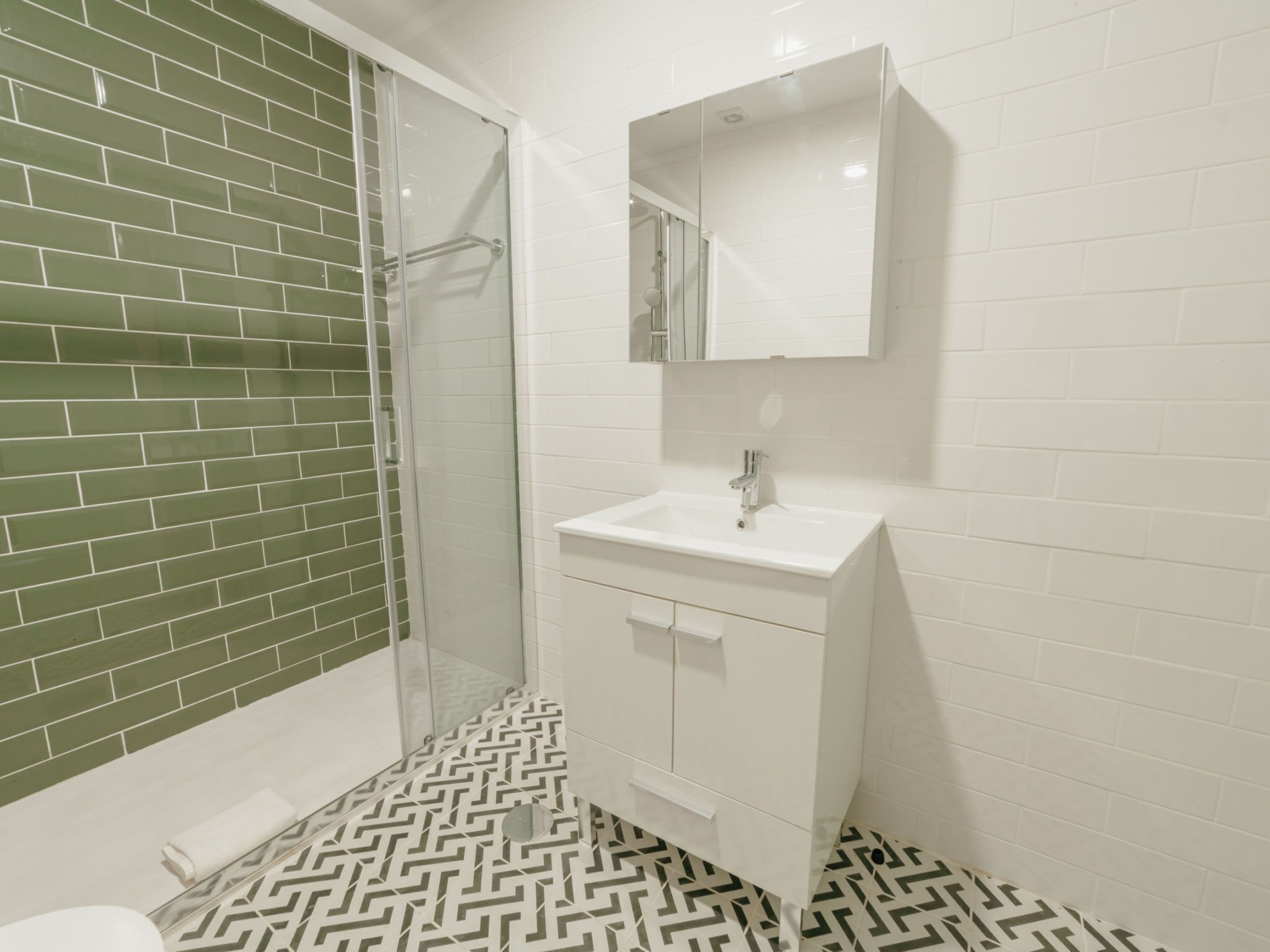 A bathroom with a shower, a sink, and a mirror.