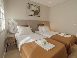 A hotel room with two beds, a chair, a painting on the wall, and a window. - Apartment  by Interhome (Porto)