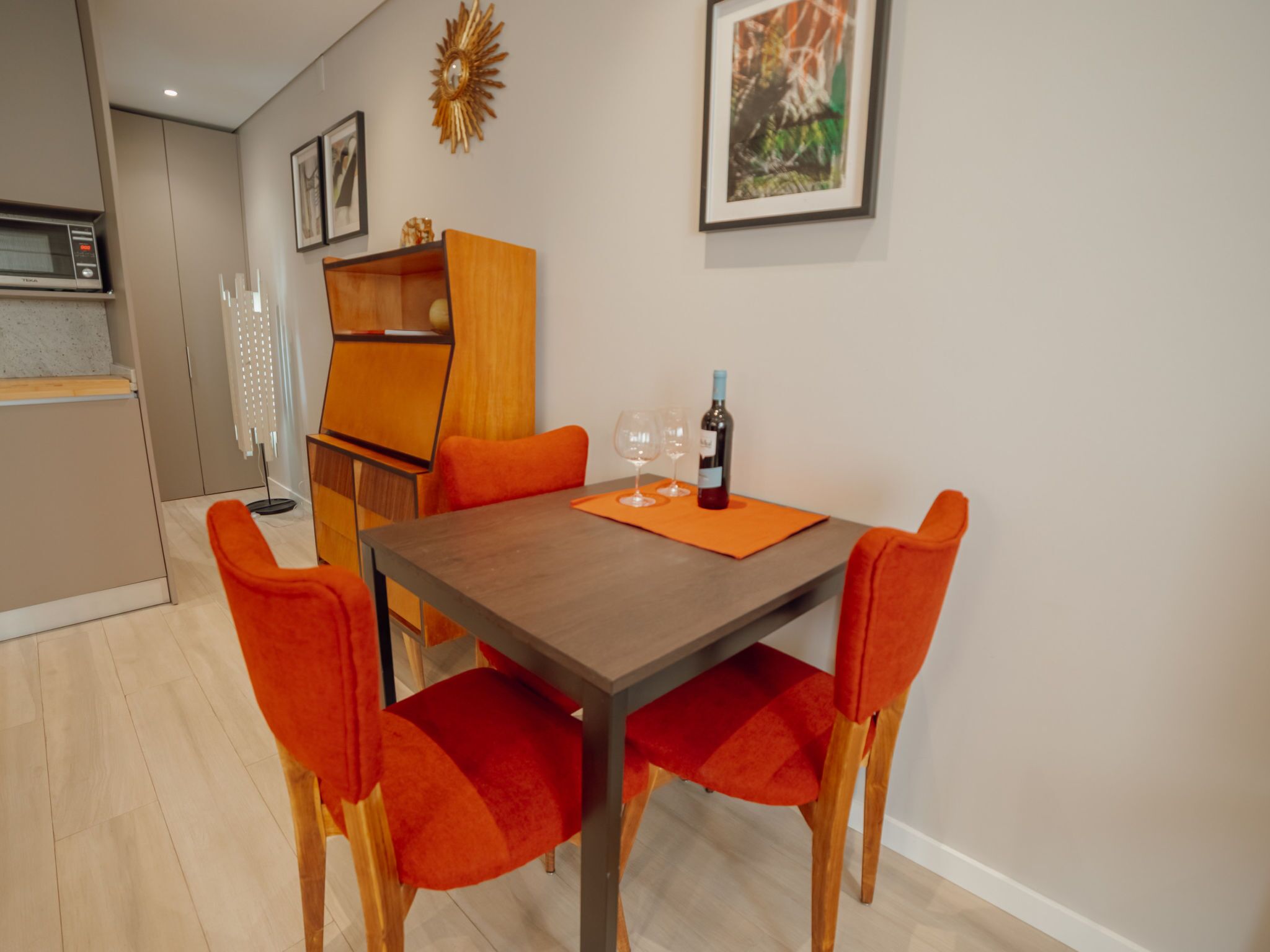A dining area with a wooden table, orange chairs, and a bottle of wine.