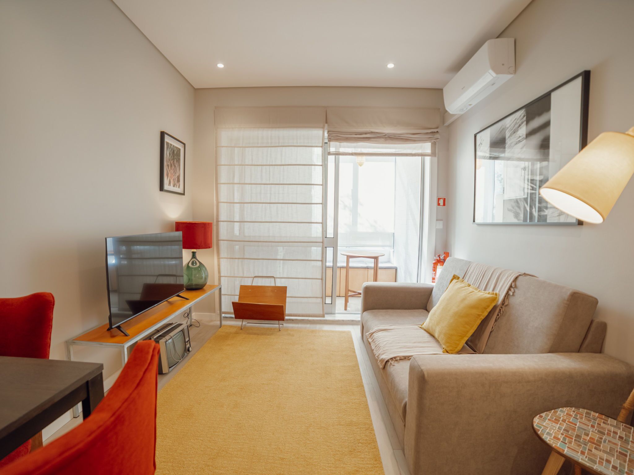 Ein modernes Wohnzimmer mit einer Couch, einem Fernseher, einem roten Sessel und einem kleinen Tisch.
