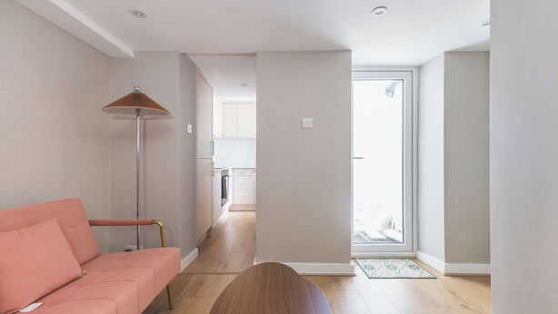 A modern interior with a sofa, a floor lamp, and a wooden table. - Stylish 2BDR 2BA Home with Patio in Putney (Greater London)