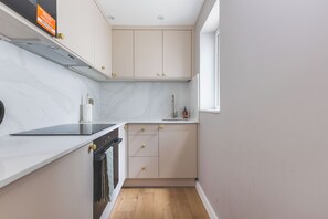 Eine kompakte Küche mit Einbauofen, Geschirrspüler und einem Fenster für natürliches Licht.