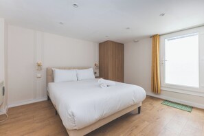 Ein Hotelzimmer mit einem großen Bett, einem Holzschrank und einem Fenster mit Vorhängen.