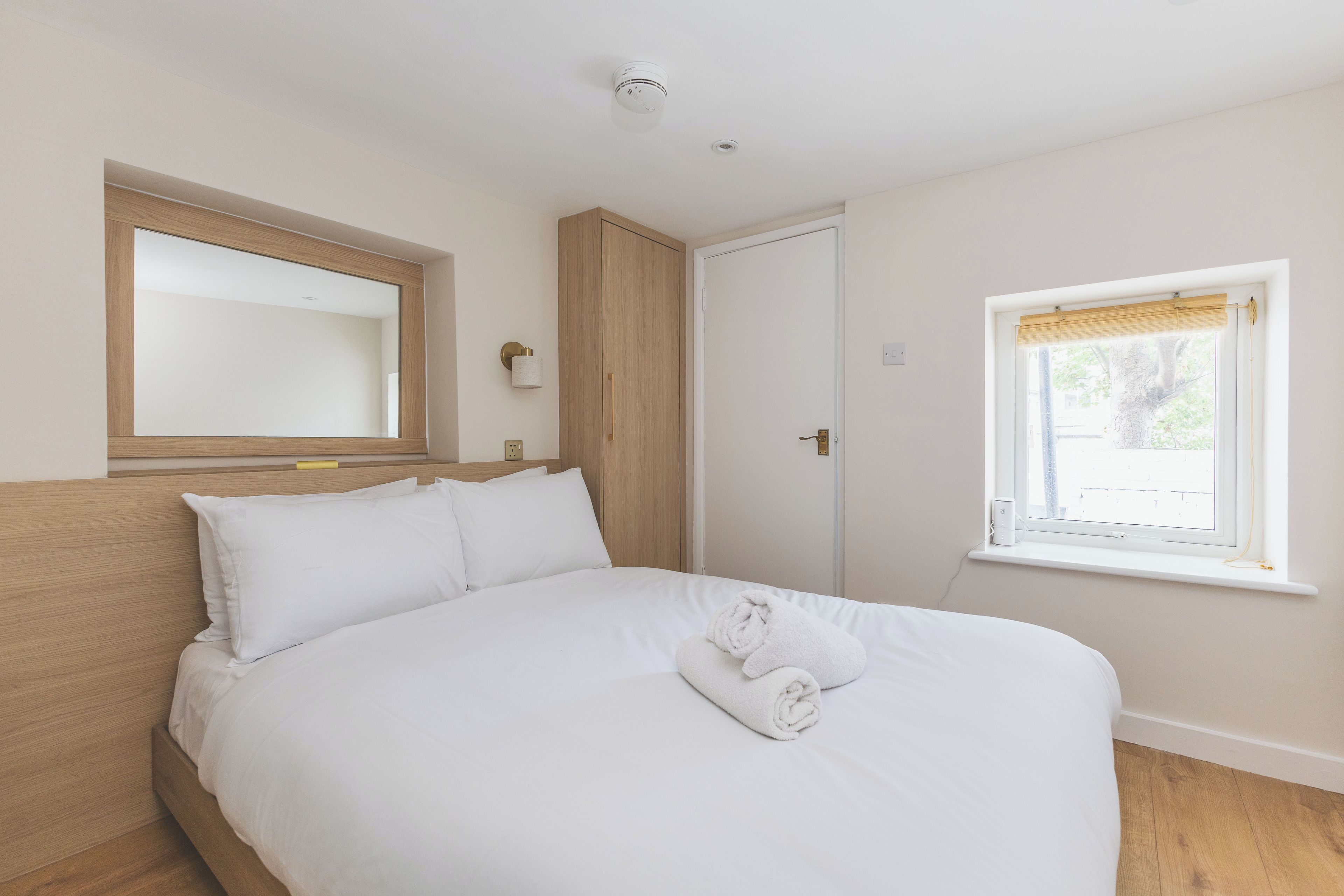 A bedroom with a bed, a window with a view, and a door.