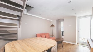 A modern interior with a staircase, a sofa, a dining table, and a kitchen area. - Stylish 2BDR 2BA Home with Patio in Putney (Greater London)