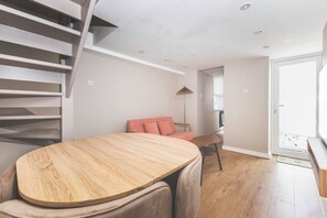 Ein modernes Interieur mit Treppe, einer Couch, einem Esstisch und einer Küchenzeile.