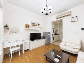 Uma sala de estar moderna com uma mesa de escritório branca, uma televisão, um sofá e uma mesa de centro.