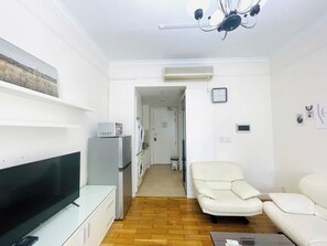 Ein Wohnzimmer mit Flachbildfernseher, Sofa, Sessel, Couchtisch und Waschmaschine.