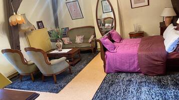 Une chambre d’hôtel comprenant un lit, deux fauteuils, un canapé, une petite table, un lustre et un miroir.