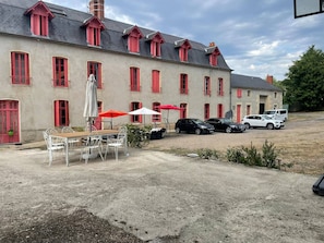 Un bâtiment doté de nombreuses fenêtres et d’un espace aménagé avec une terrasse pour s’asseoir à l’extérieur.