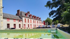 A swimming pool with a view of a row of buildings with red shutters and a clear blue sky.