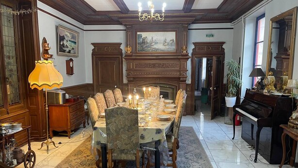 A formal dining room with a large table set for six, surrounded by chairs, a chandelier, and a fireplace.