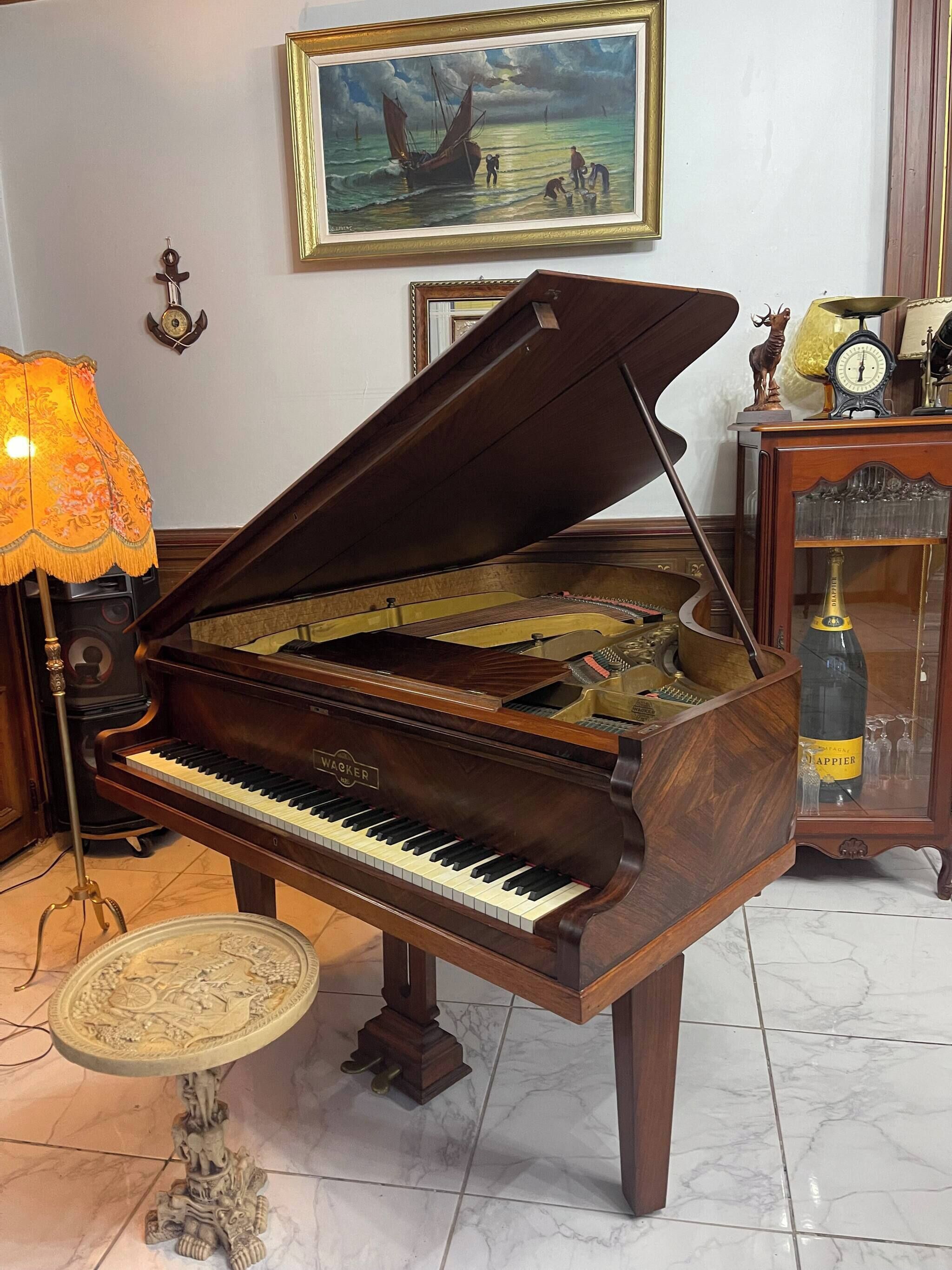 A grand piano in a room with a painting on the wall, a lamp, and a clock on a side table.