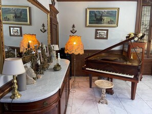 A grand piano in a spacious room with marble flooring, ornate wall decorations, and a large mirror. - 18th century Castle of Clairefontaine (Garchizy)