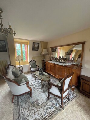 A traditional living room with a fireplace, a dining table, and two armchairs.