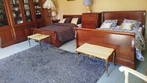 A bedroom with a double bed, a nightstand, a dresser, a small table, and a chair.