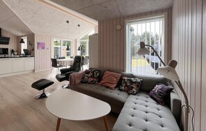 Ein modernes Wohnzimmer mit einer Couch, einem Couchtisch und einem Essbereich mit Stühlen und einem Tisch.