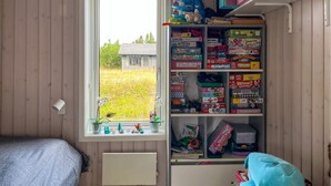Una habitación con ventana, paredes de madera, una cama y un estante con varios juegos de mesa.