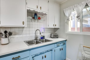 A kitchen with white cabinets, a double sink, and a toaster.