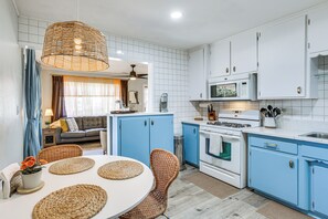 A modern kitchen with blue cabinets, a white stove, and a dining area with wicker chairs and a round table. - 2 Mi to Imperial Beach Pier! Extended Stay, Patio (Imperial Beach)