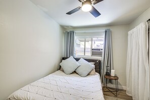 A bedroom with a bed, a ceiling fan, a window with curtains, and a bedside table. - 2 Mi to Imperial Beach Pier! Extended Stay, Patio (Imperial Beach)