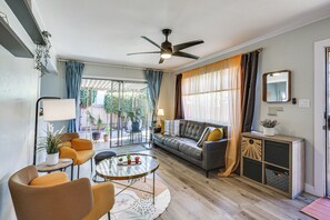 A modern living room with a sofa, coffee table, and chairs. There is a ceiling fan, a window with curtains, and a potted plant. - 2 Mi to Imperial Beach Pier! Extended Stay, Patio (Imperial Beach)