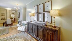 A well-lit living room with a dark wood console table, a striped armchair, and a dining area with a wooden table and chairs. - Cozy Sylvester Apartment w/ Fireplace (Sylvester)