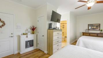 A bedroom with a bed, a dresser, a television, and a ceiling fan.