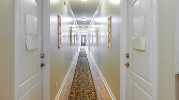 A hotel hallway with white doors, a patterned carpet, and a ceiling light fixture. - Cozy Sylvester Apartment w/ Fireplace (Sylvester)