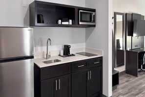 A modern kitchen with a stainless steel refrigerator, a microwave, a coffee maker, and a sink.