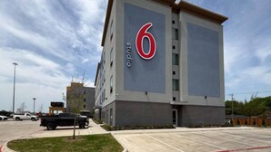A modern building with a prominent '6' sign, likely a hotel or apartment complex, with a parking lot in front. - 2 Queen Beds|Non-Smoking,Kitchen (Dallas)