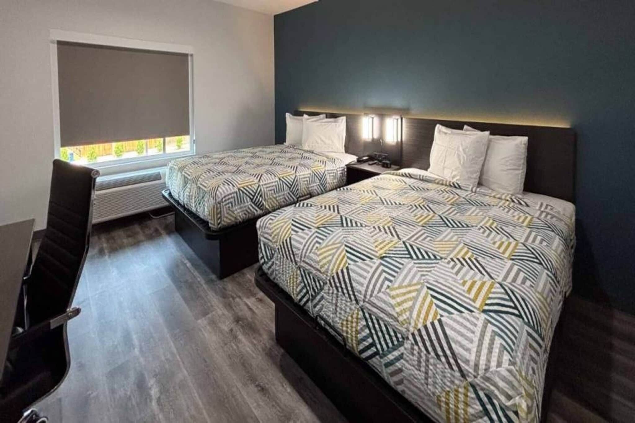 Une chambre d’hôtel avec deux lits, un bureau et une chaise.