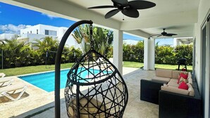A covered outdoor area with a pool, a ceiling fan, and a swing chair. - Villa Oasis del Mar 4 (Sosúa)