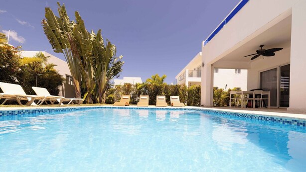 A clear blue swimming pool with lounge chairs and a covered seating area. - Villa Oasis del Mar 4 (Sosúa)