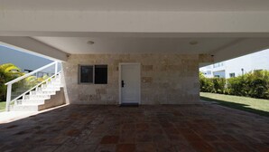 A covered outdoor area with a stone wall, a door, and a staircase leading to an upper level. - Villa Oasis del Mar 4 (Sosúa)