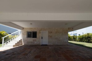 A covered outdoor area with a stone wall, a door, and a staircase leading to an upper level. - Villa Oasis del Mar 4 (Sosúa)