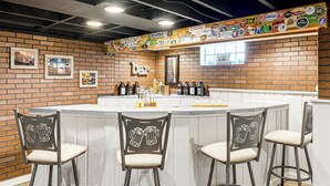 Een bar met een bakstenen muur, een wit aanrecht en barkrukken met afbeeldingen van bierkannen.