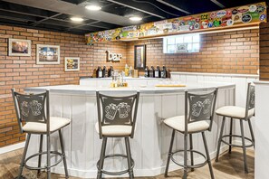 A bar area with a brick wall, a white countertop, and bar stools with beer mug designs. - Close to Downtown Milwaukee & Mid-Term Friendly! (Wauwatosa)