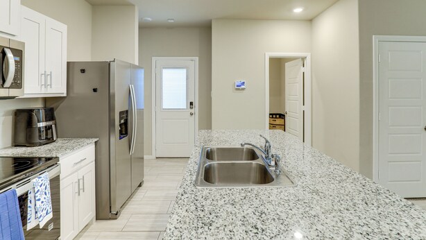 A modern kitchen with stainless steel appliances, a granite countertop, and a double sink. - Family-Friendly Fort Worth Home: Private Yard (Fort Worth)