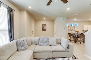 A living room with a sectional sofa, a dining area with a table and chairs, and a kitchen in the background. - Family-Friendly Fort Worth Home: Private Yard (Fort Worth)